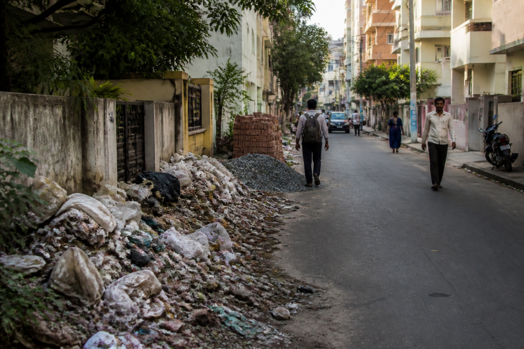 Garbage and construction debris accumulated along a residential road in Bengaluru's Binny Crescent