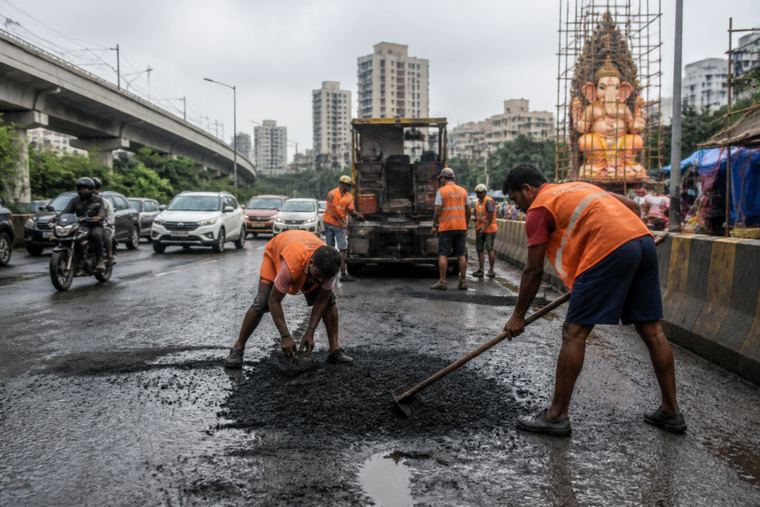 Workers repairing a damaged road on a Ganesh festival procession route in Navi Mumbai