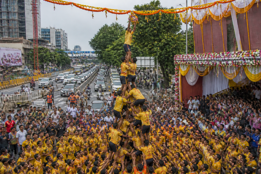 Govinda teams form a human pyramid during a Dahi Handi event on a busy road in Thane