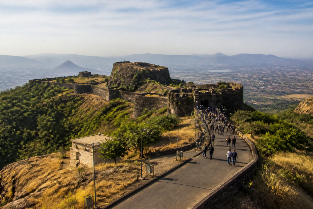 Maharashtra tourism growth represented by visitors near a historic fort with a city and regional landscape in the background