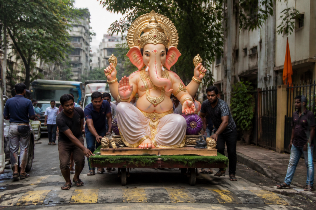 A large Ganesh idol being transported on a trolley through a Mumbai street during Ganeshotsav preparations