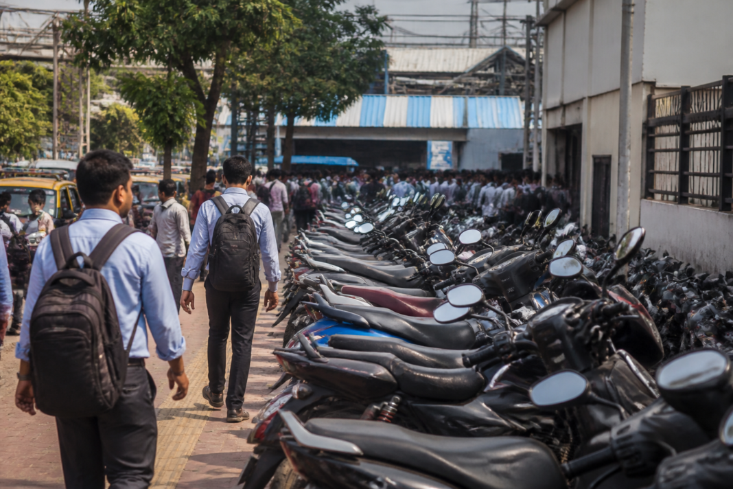 Two-wheelers parked along the road and footpath outside Bhayandar railway station's west entrance