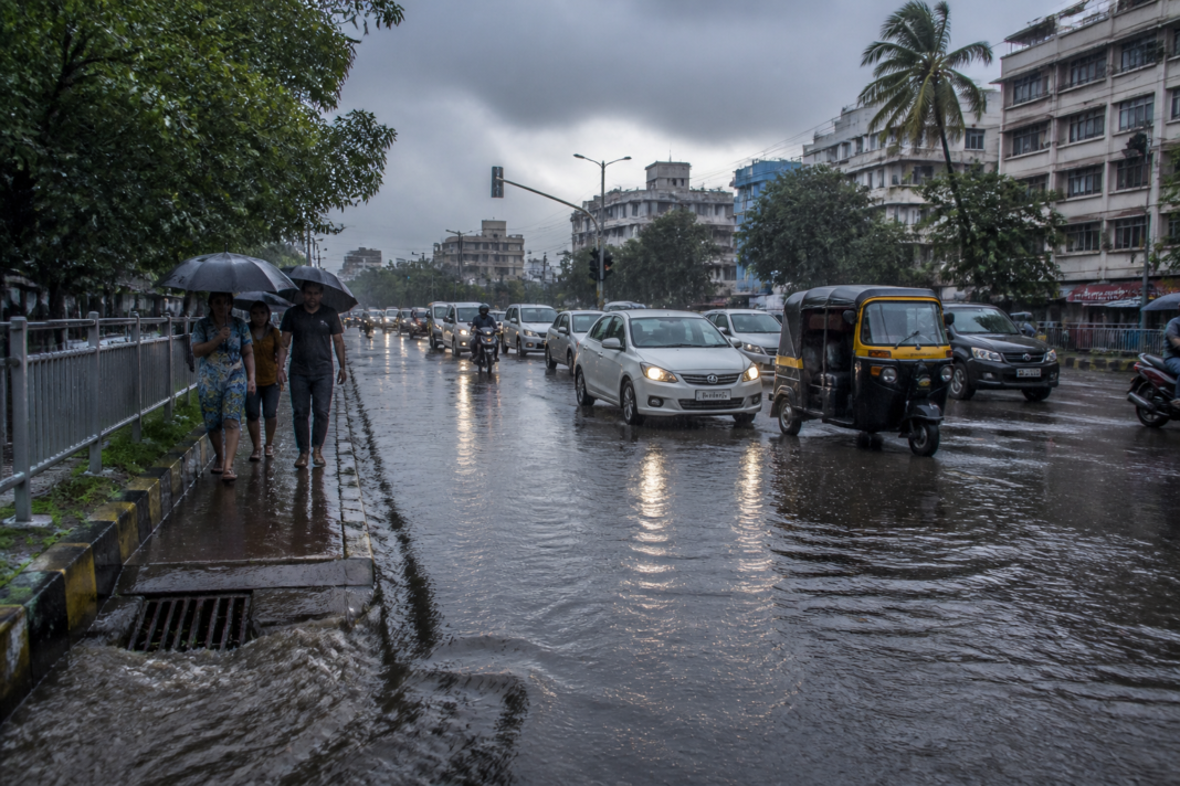 IMD rain alert coverage showing heavy monsoon rain on an Indian urban road