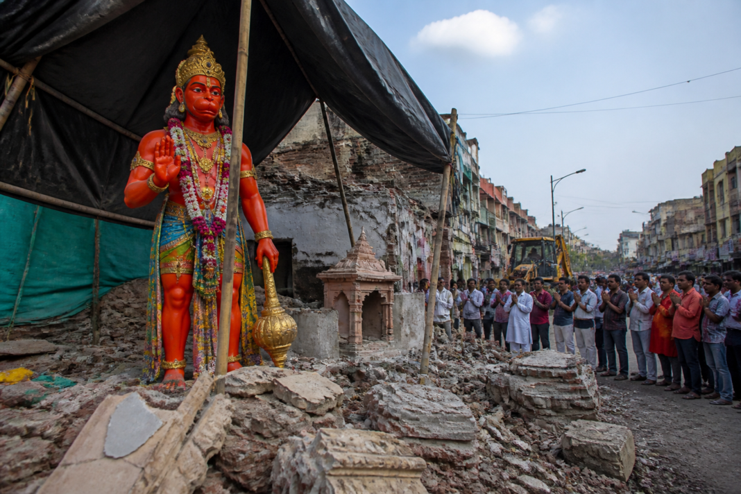 The Khade Hanuman idol standing beneath a waterproof tent beside the remains of its dismantled temple in Ujjain