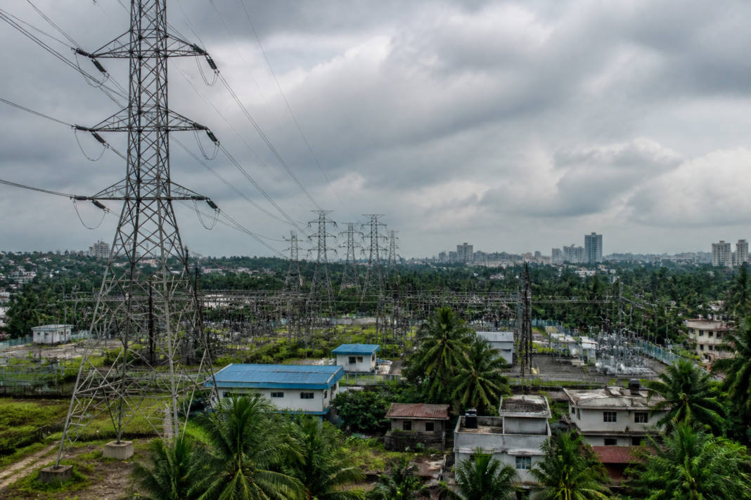 Kerala power crisis reflected in an electricity substation and transmission lines under an overcast sky.
