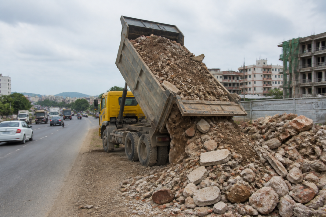 Vasai debris dumping along a highway beside a construction waste truck