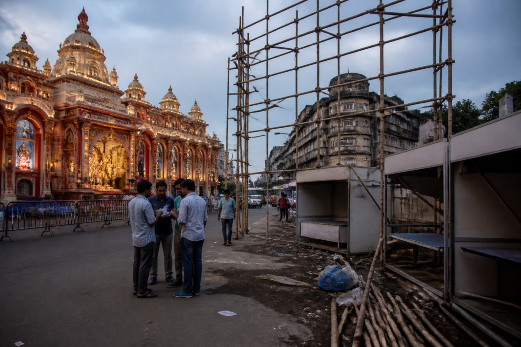 Kolkata Durga Puja advertising structures awaiting sponsors near a decorated pandal.