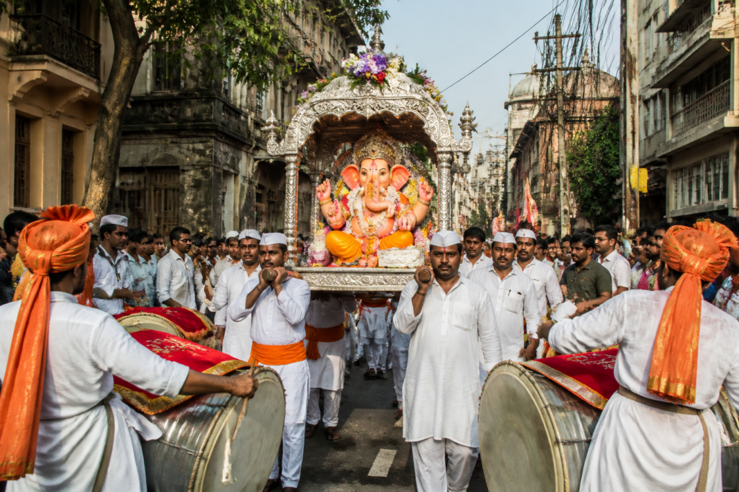 Pune Ganpati sthapana procession with an idol carried through a central Pune street