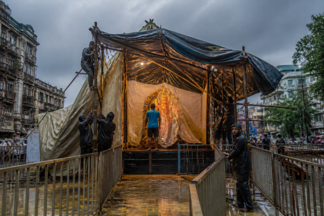 Mumbai Ganeshotsav rain affecting a covered Ganesh mandal pandal and devotee queue area