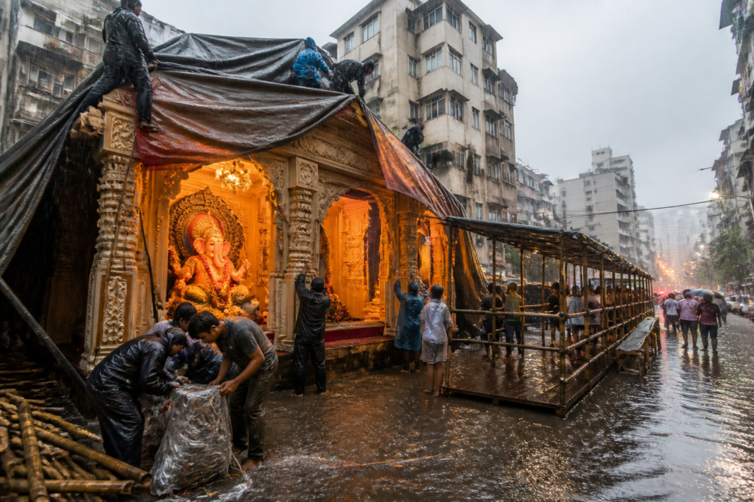 Mumbai Ganeshotsav rain affecting a covered festival pandal and devotee waiting area