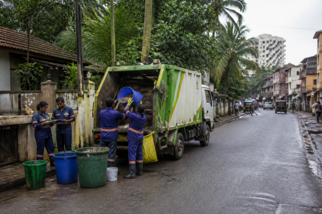 Mangaluru waste management workers and a collection vehicle on a city street