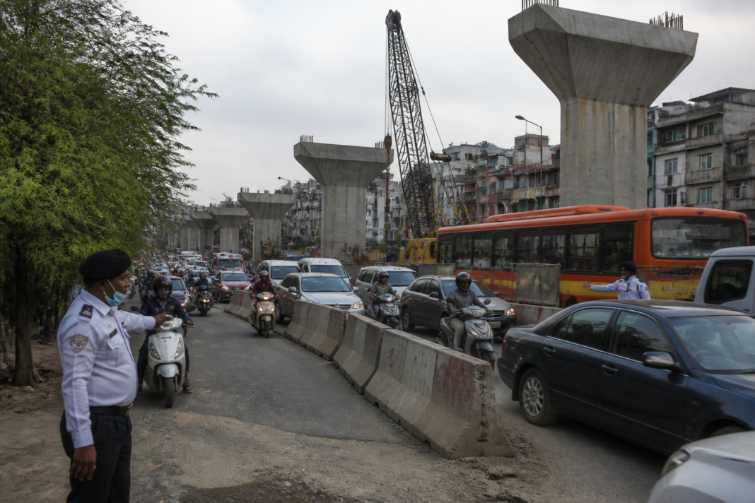 Modi Mill flyover construction narrowing a Delhi road as vehicles move through heavy traffic.