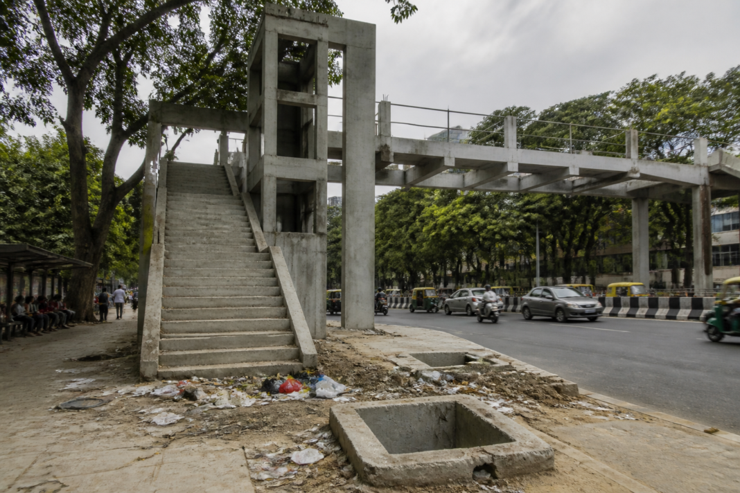 Incomplete Race Course Road skywalk in Bengaluru with unfinished lift access and garbage on the stairs