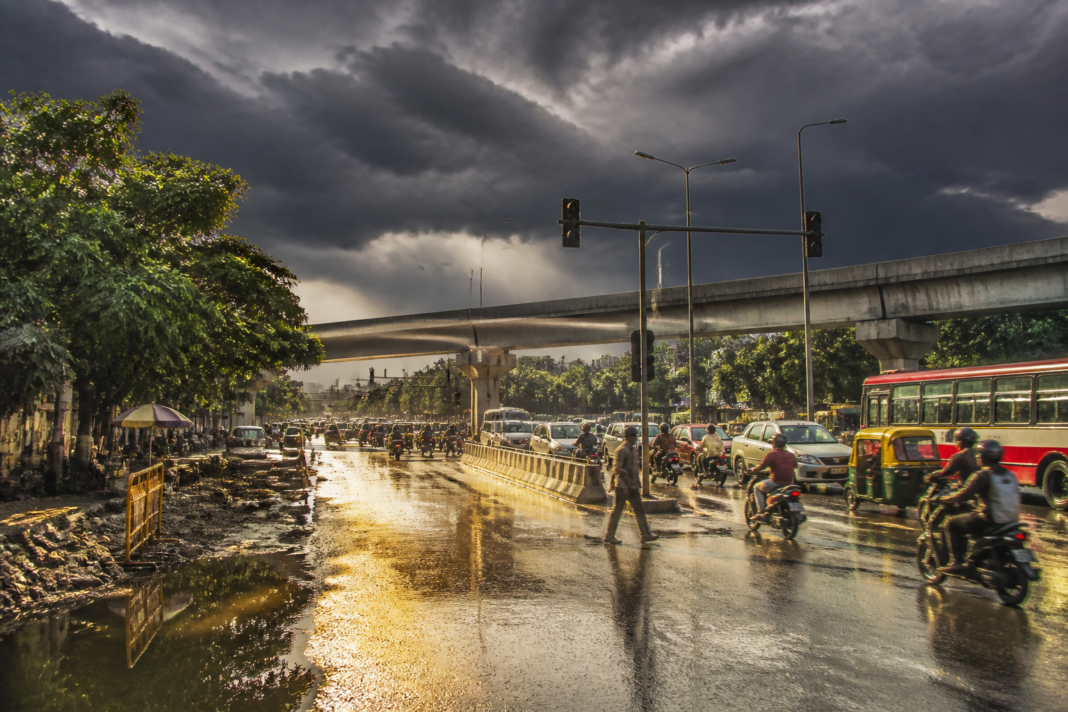 Bengaluru temperature surge over a hot city street beneath dark monsoon clouds