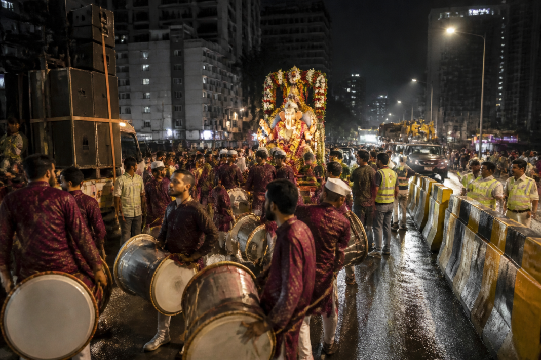 Thane Ganpati immersion procession with drums and sound systems near a crowded city road