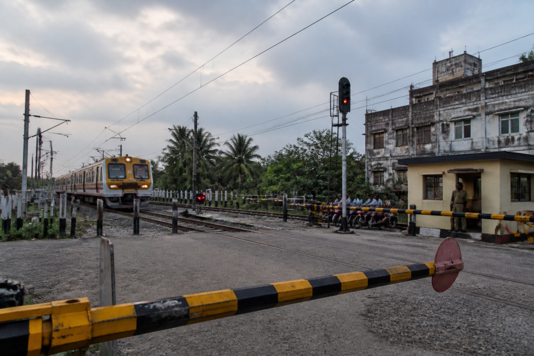 Level crossing safety at a railway gate in Hooghly, West Bengal, with tracks and road barriers visible.