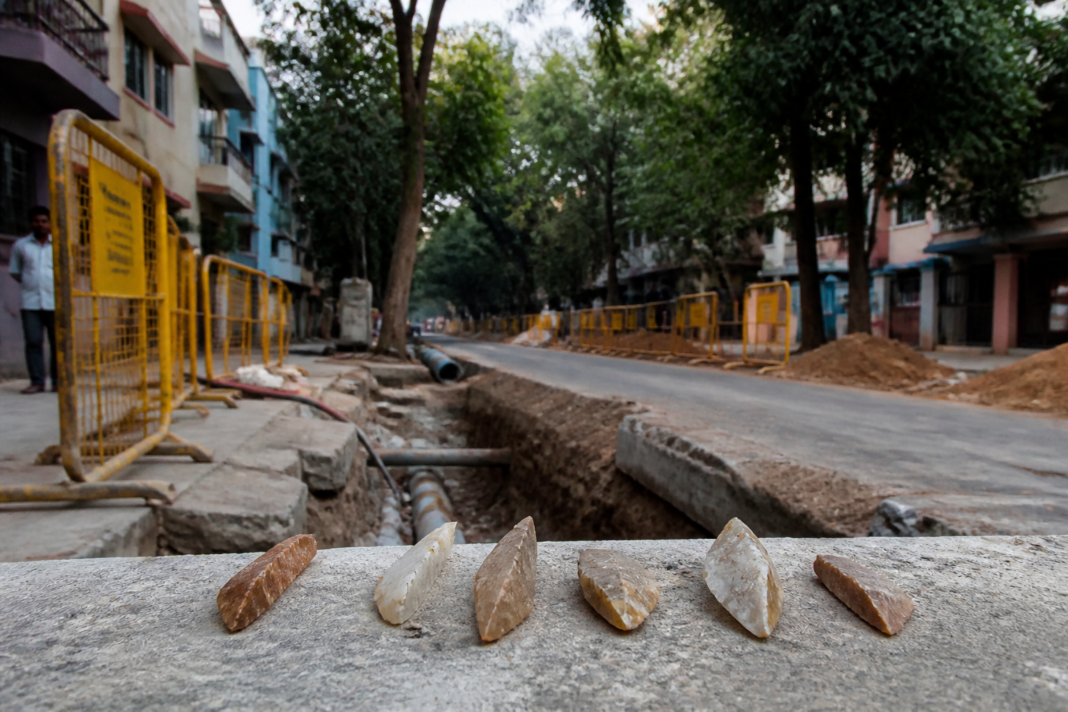 Bengaluru Palaeolithic discovery represented by stone tools beside an urban pipeline repair site.