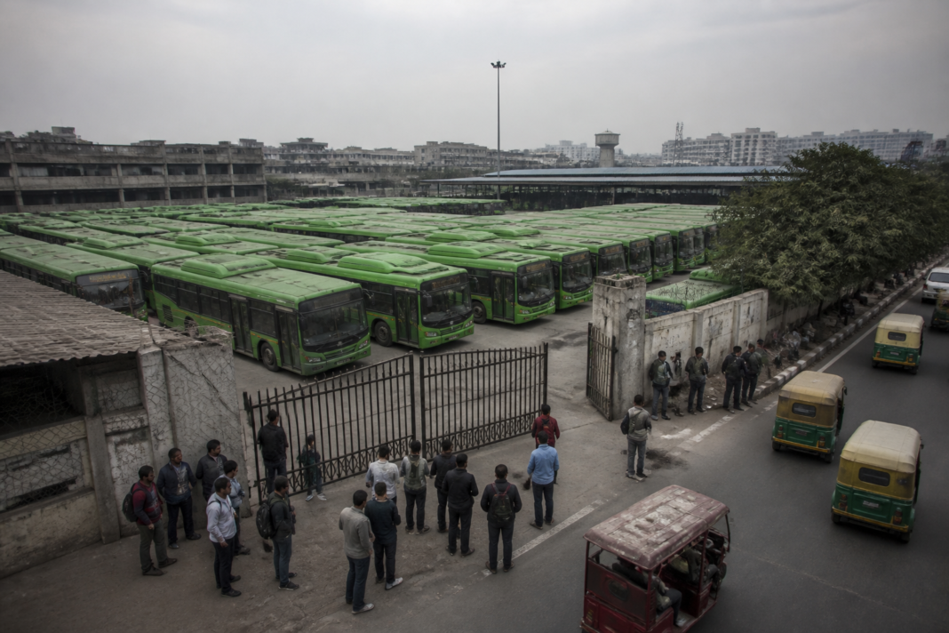 Delhi DTC strike leaves buses parked at a depot as passengers seek alternative transport