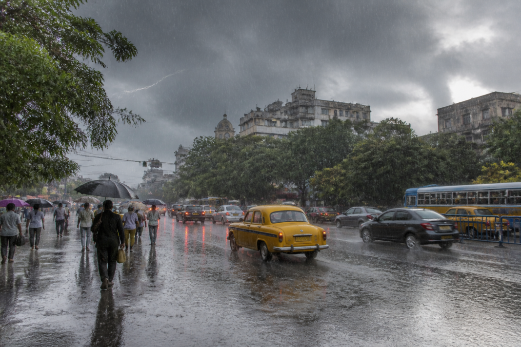 Kolkata rain falling over a city street as dark monsoon clouds cover the skyline