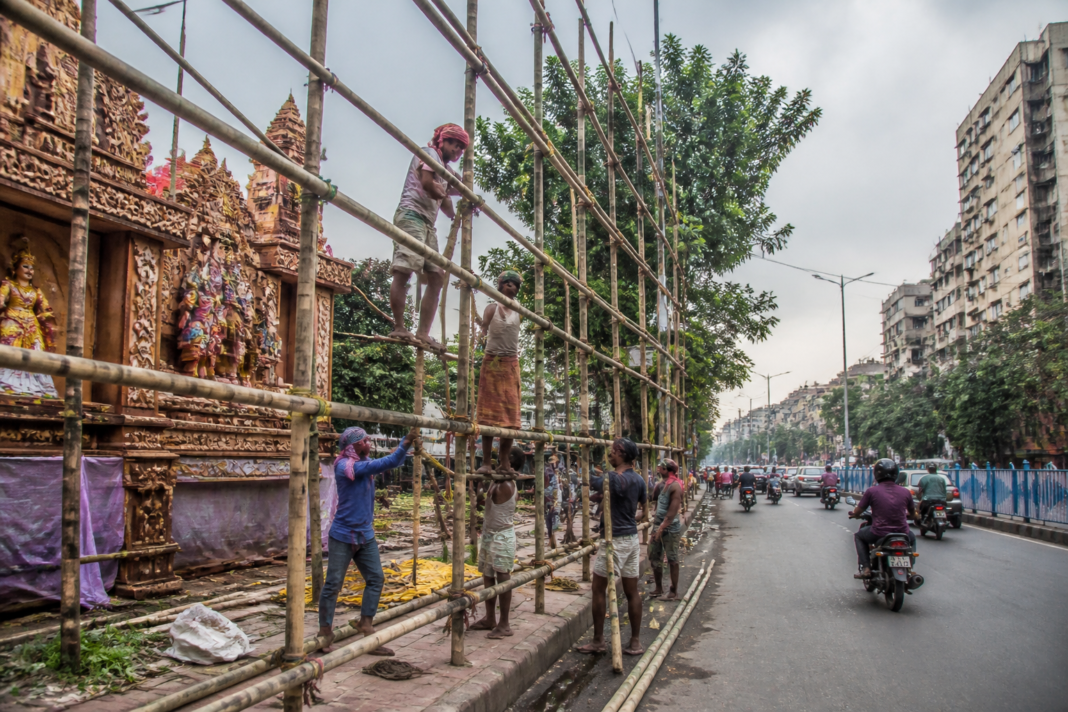 Kolkata hoardings and bamboo advertising frames near a Durga Puja pandal