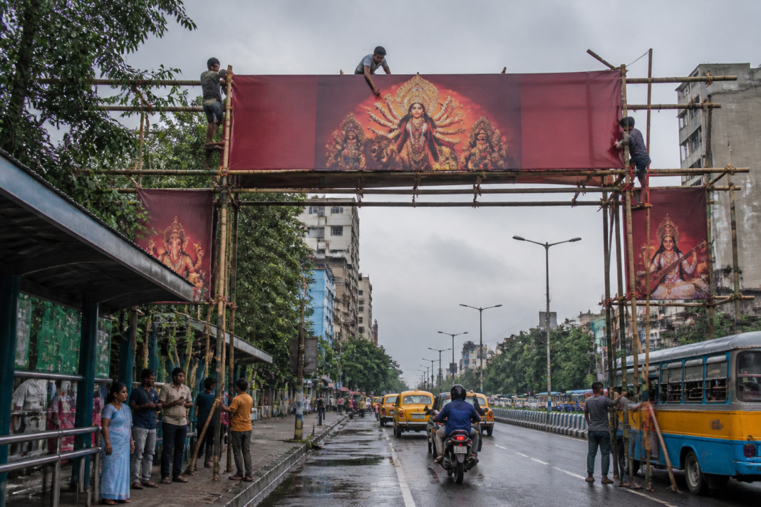 Kolkata Durga Puja hoardings on a temporary bamboo structure beside a city road