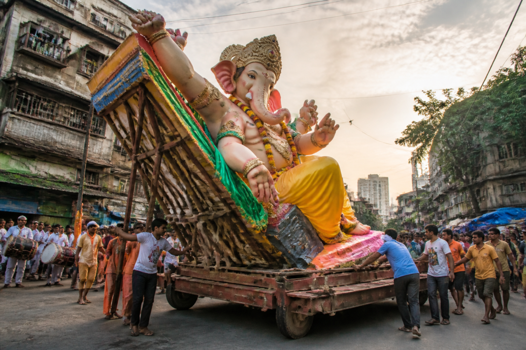 Large balancing Mumbai Ganesh idol displayed during a festival procession.