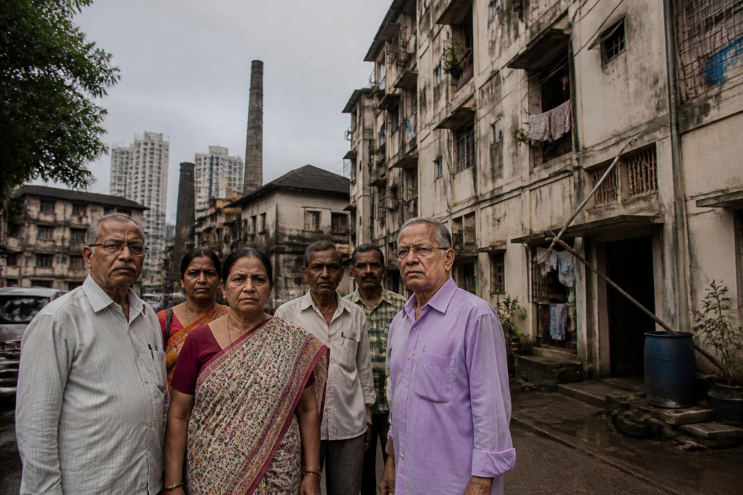 Mill workers housing backlog in Mumbai, with families waiting outside a residential building