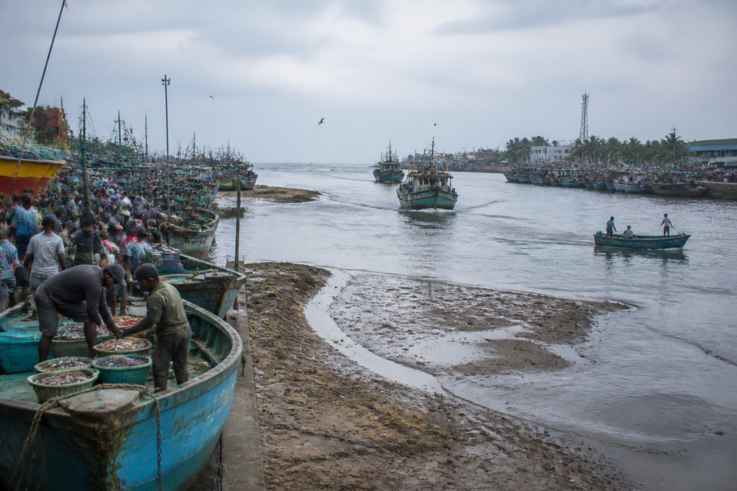 Mangaluru fishing harbour with boats navigating silted waters near the estuary mouth