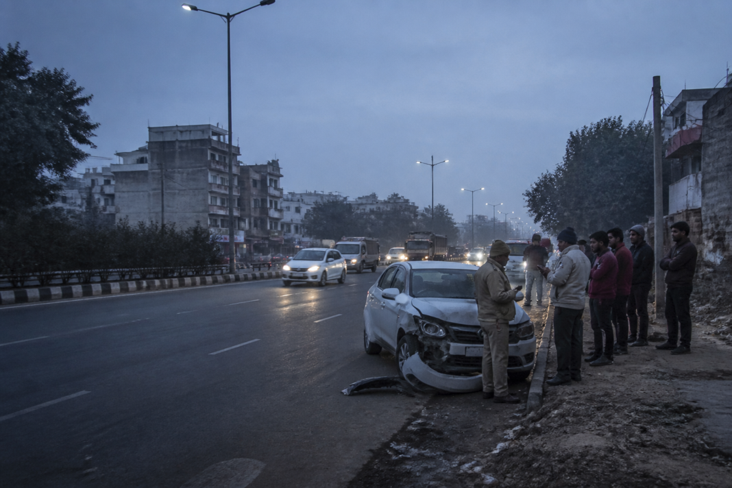 Nangloi hit-and-run scene on a Delhi road with a damaged car and roadside pedestrians