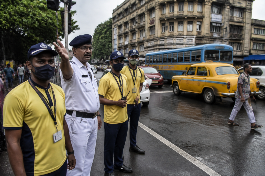 Kolkata civic volunteers standing near a city traffic junction under police supervision