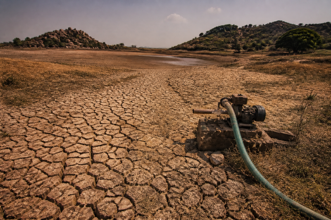 Karnataka drought landscape with a dry agricultural field and a depleted village water tank