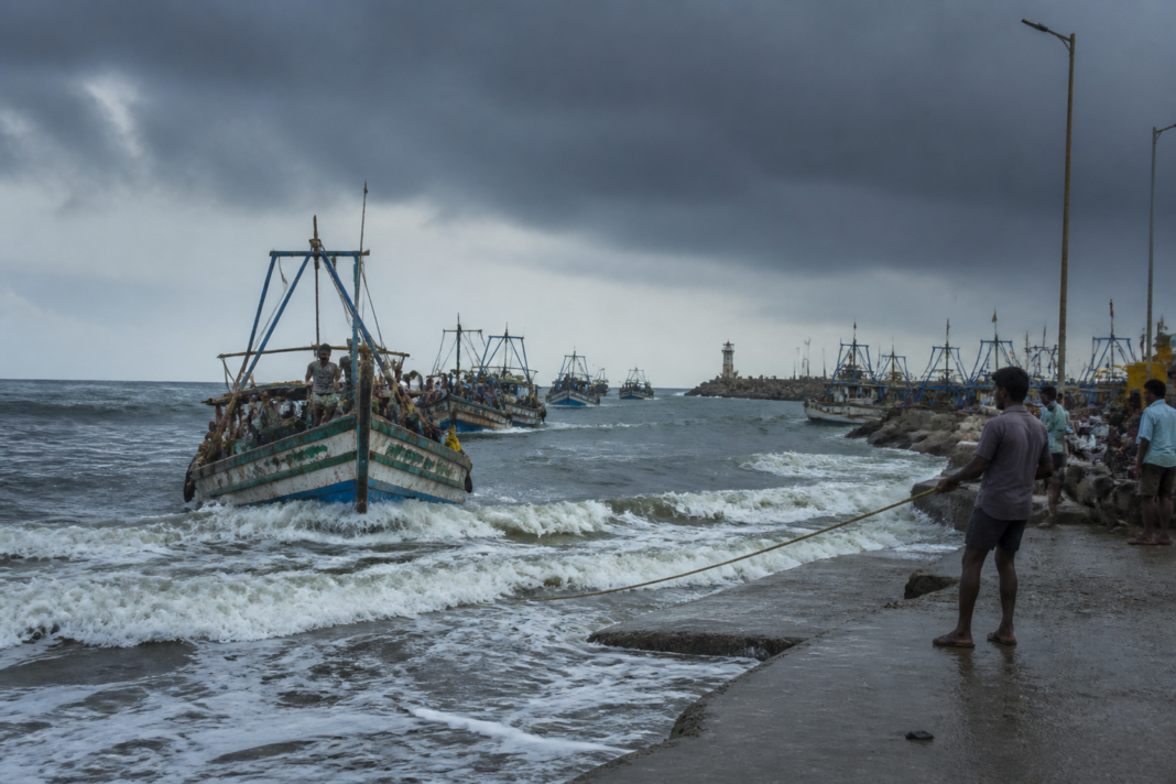 Andhra Pradesh fishermen returning boats to shore amid a rough sea warning