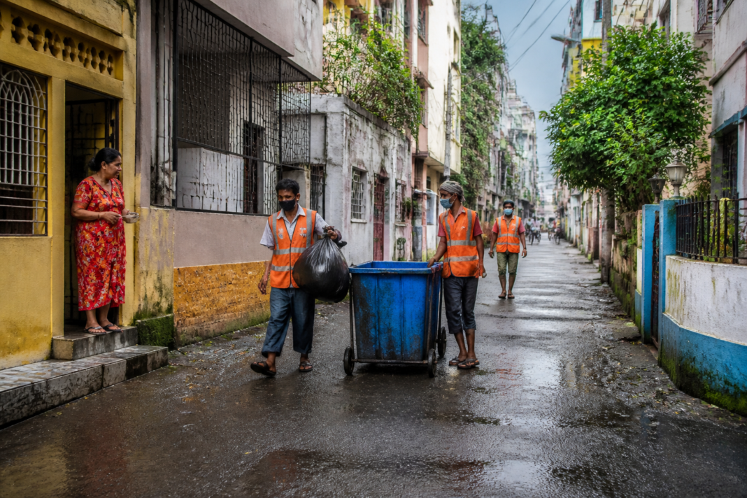 Kolkata dengue prevention workers collecting household waste near a residential neighbourhood.