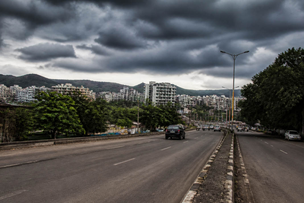 Pune rainfall deficit shown through a dry urban road under monsoon clouds