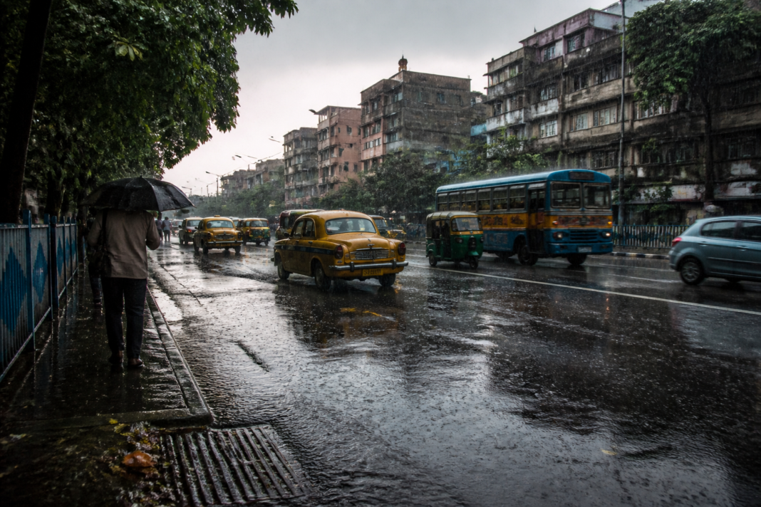 Kolkata heavy rain over a waterlogged urban street under dark monsoon clouds