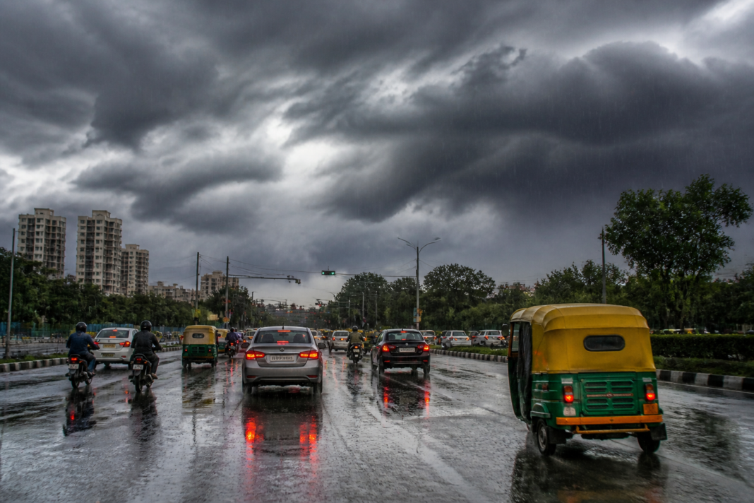 Delhi weather forecast showing commuters and traffic under dark monsoon clouds