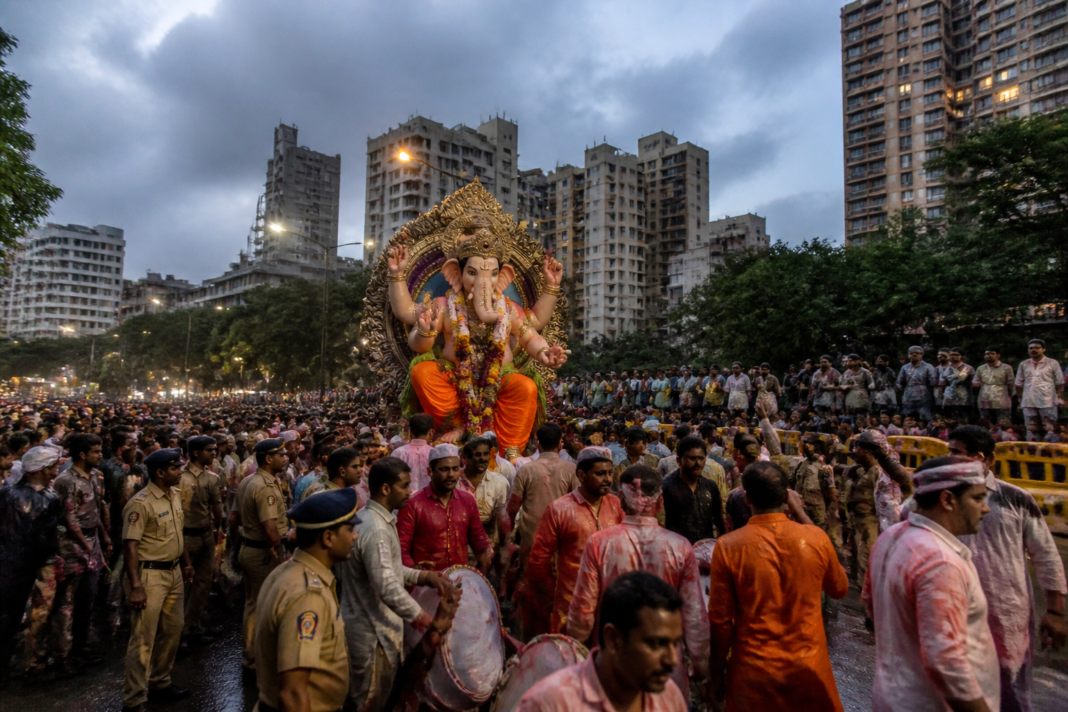 Mumbai Ganesh Visarjan procession moving through a crowded city street with drums and devotees.