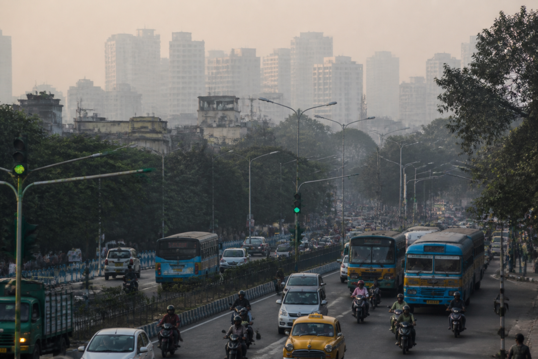 Kolkata air pollution over an urban road with vehicles and a hazy skyline