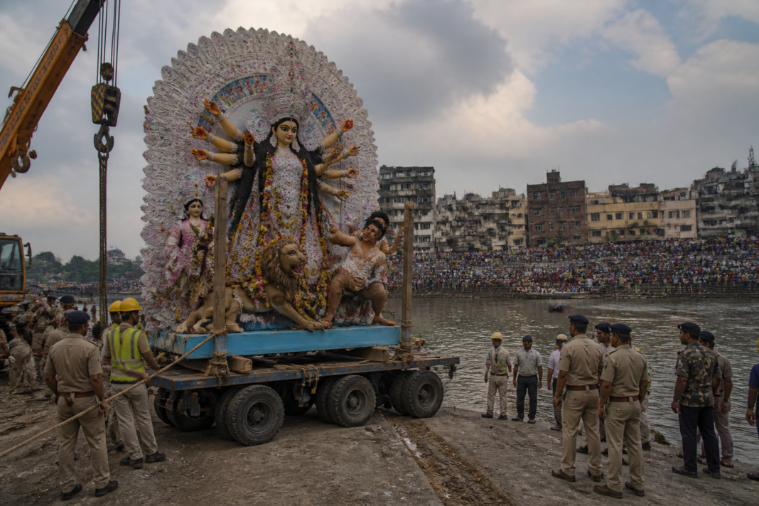 Kolkata Durga idol immersion preparations at a river ghat with a trolley and crane equipment