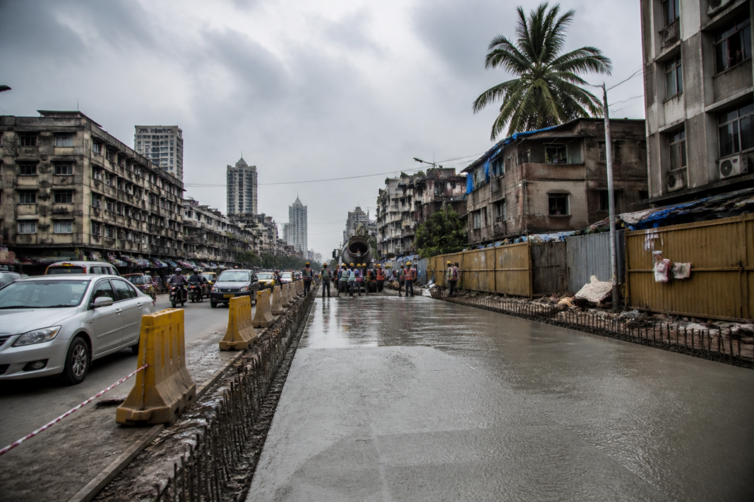 Mumbai road concretisation work underway on a city street with construction barriers and traffic