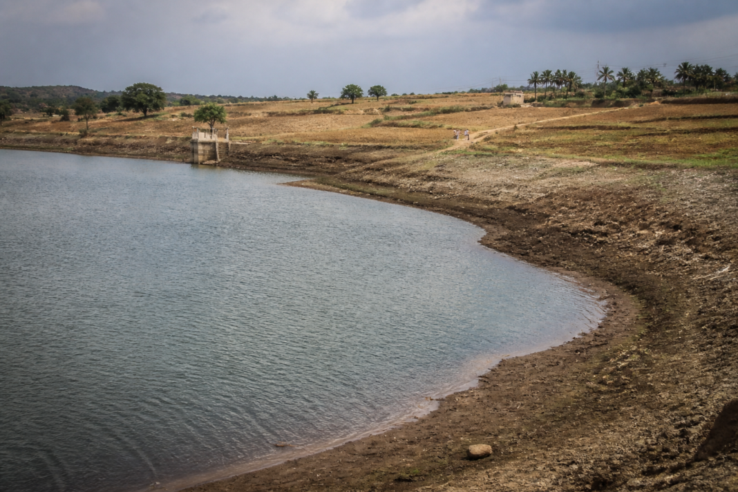 Weak monsoon 2026 leaves an Indian reservoir below normal storage levels near farmland.