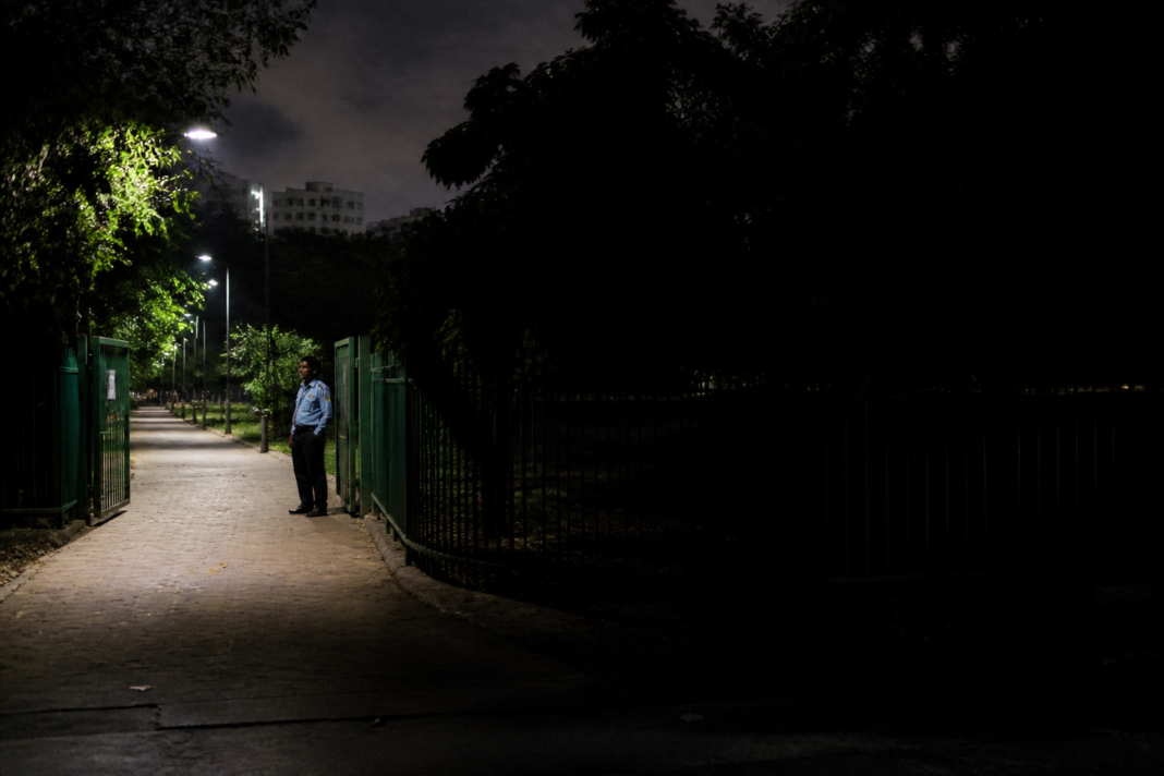 Delhi dark spots near a poorly lit park gate with a security guard and surrounding shadows