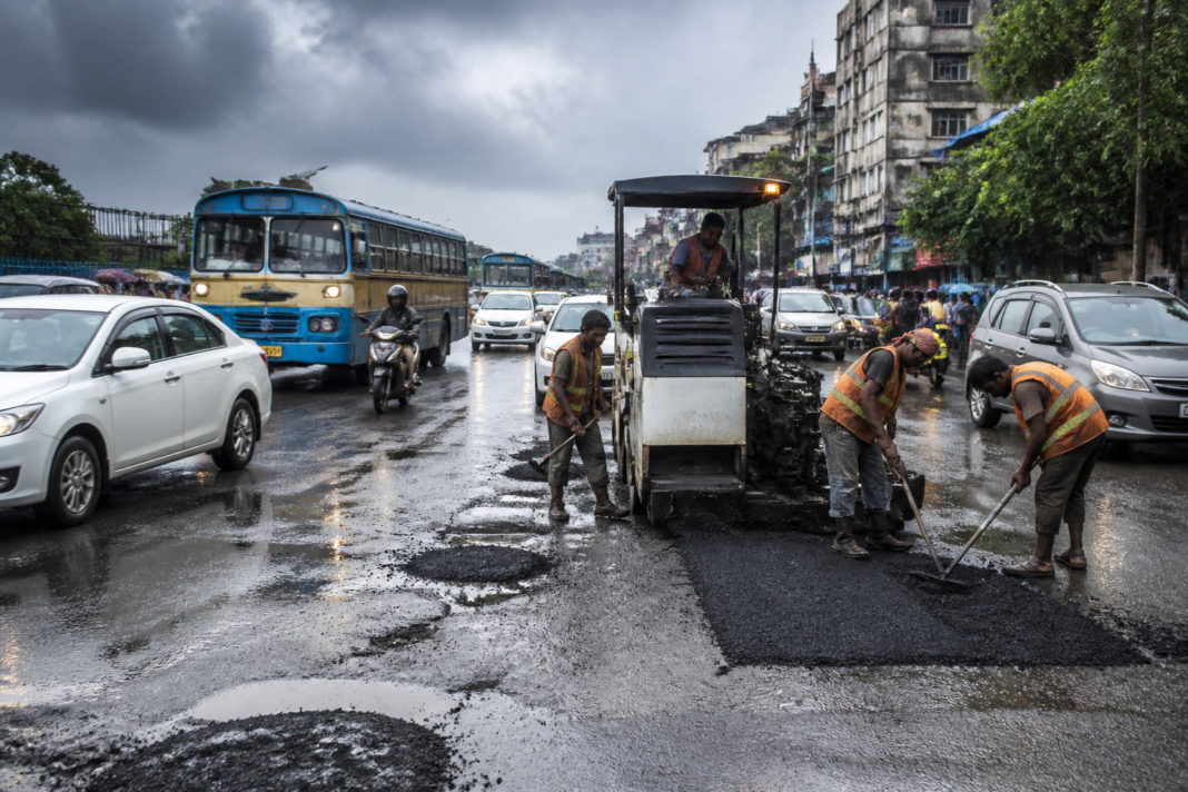 Kolkata road repairs underway on a pothole-filled city street during the rainy season
