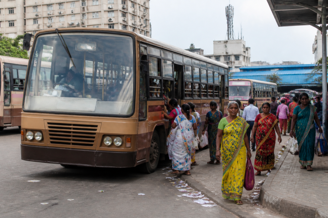 Tamil Nadu free bus scheme buses operating on a busy urban road with women passengers boarding