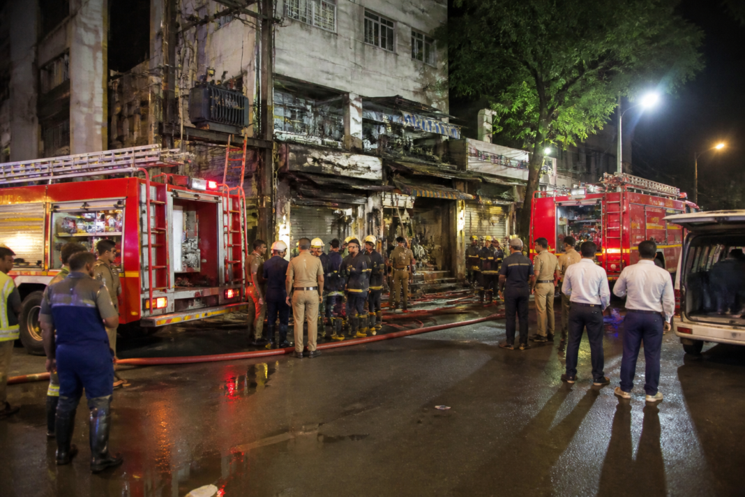 Firefighters responding to a Thane fire near Talao Pali beside a damaged commercial shop.