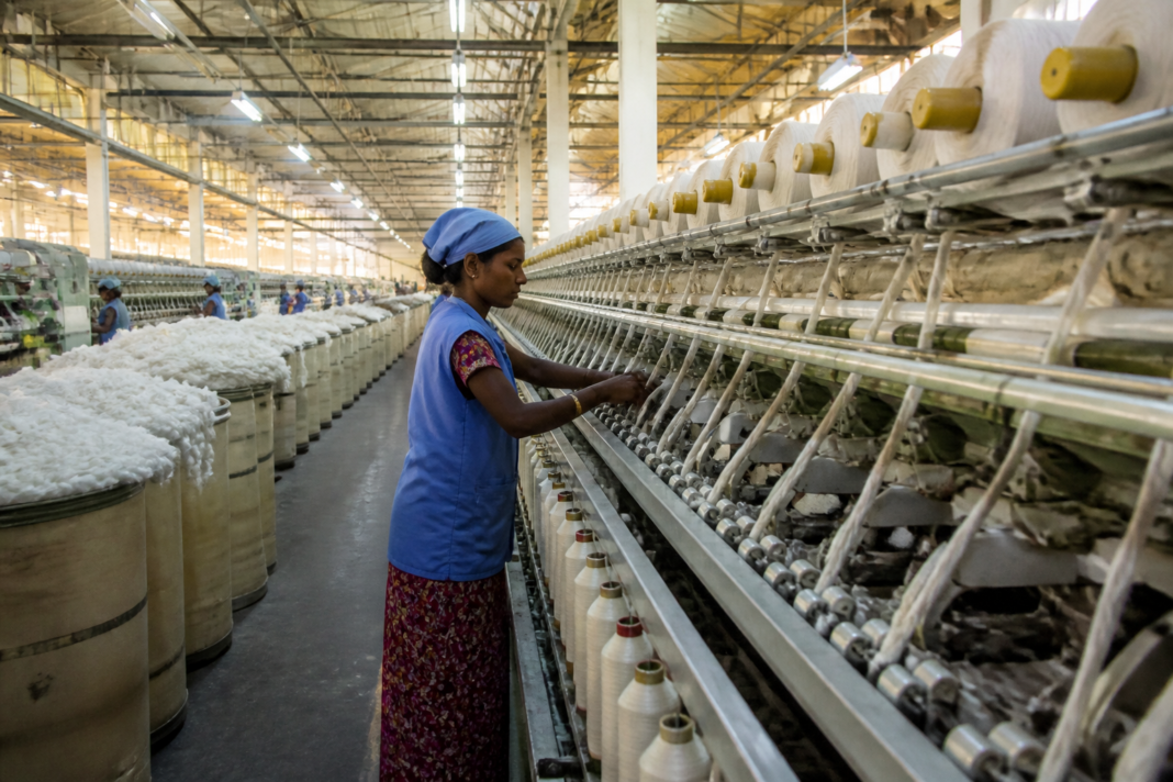 Indian textile industry workers in a Tamil Nadu spinning mill with cotton fibres and machinery.