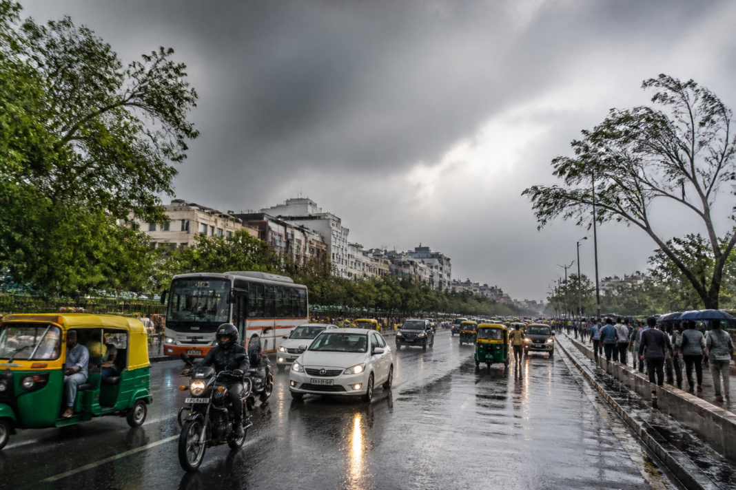 Delhi weather tomorrow with dark clouds and light rain over a busy city road