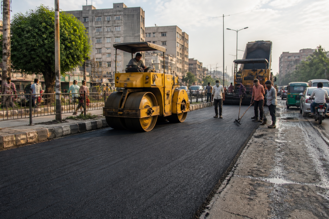 Ahmedabad road resurfacing work underway on an urban street with civic crews and machinery