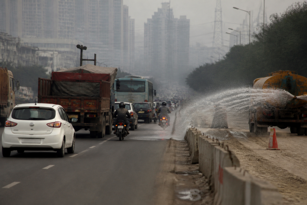Delhi pollution plan with traffic, road dust and electric vehicles on an NCR urban road