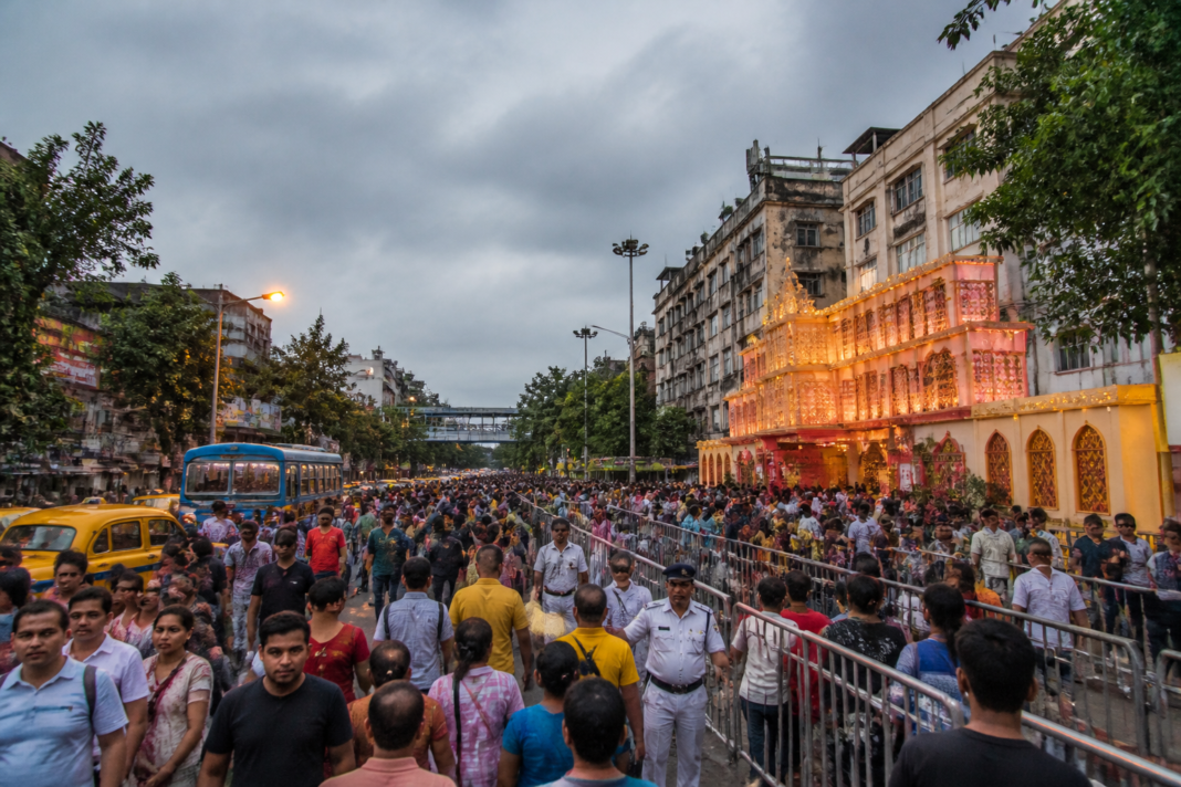 Kolkata Durga Puja crowd plan showing pedestrians and traffic near a busy pandal route.